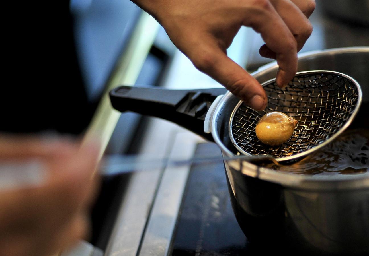 A spherified food item, being lifted out of a bath in the El Bulli kitchen