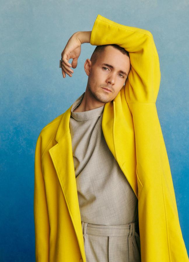 Jonah Hauer-King wearing a yellow jacket in front of a blue studio background