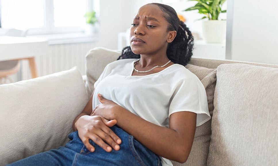 woman on sofa with stomach pain