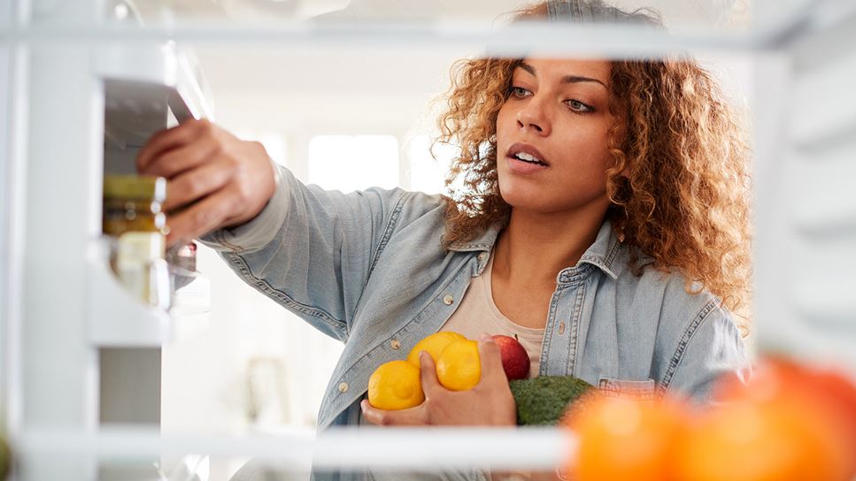 A woman is placing groceries into the refrigerator promptly after purchasing to keep foods fresh and in the correct places.