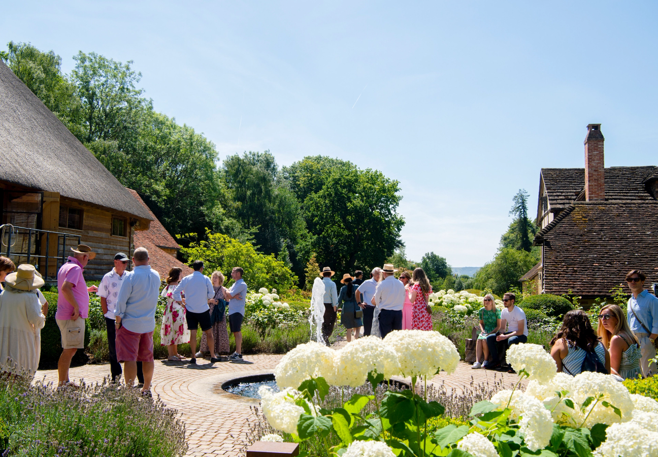 Gravetye Manor garden and fountain surrounded by people on a sunny day